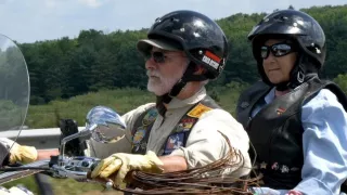 Two individuals on a motorcycle wearing helmets and jackets