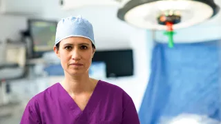 A female surgeon in medical attire standing inside an operating room