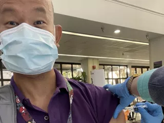 Man in a mask receives a vaccination in the arm