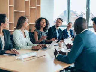 A group of professionals sitting around a table in a boardroom meeting.